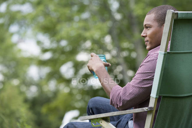 Чоловік сидить у кріслі в саду — стокове фото