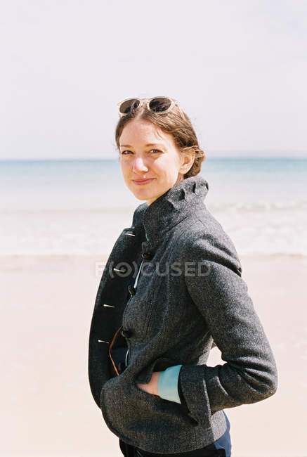 Жінка в пальто на пляжі . — стокове фото