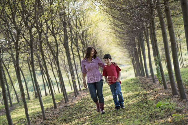 Donna e bambino che camminano su un viale di alberi . — Foto stock