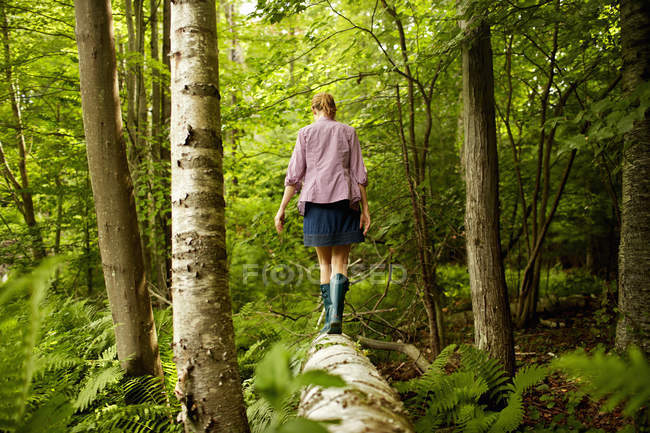 Donna che cammina lungo un tronco caduto — Foto stock