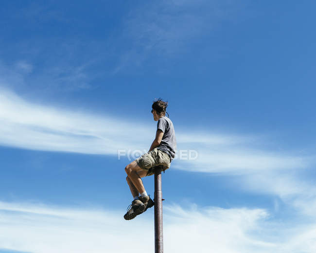 Homem sentado e equilibrando no poste de metal — Fotografia de Stock