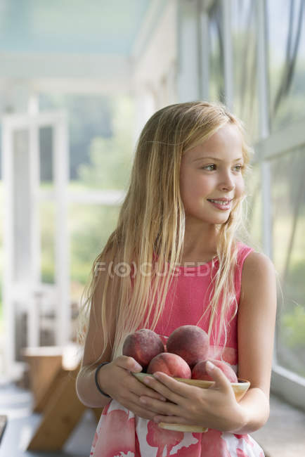 Girl holding fresh peaches. — Stock Photo