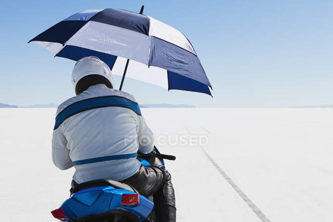 Motorradfahrer versteckt sich unter einem Regenschirm — Stockfoto