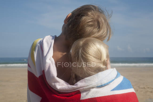 Dos niños compartiendo una toalla . - foto de stock