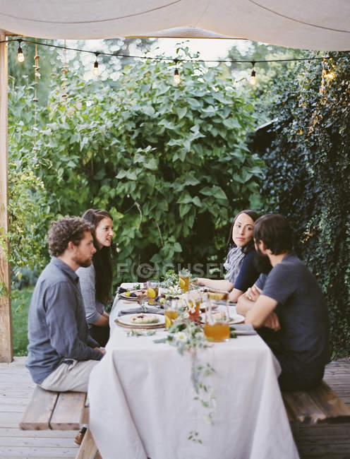 Persone sedute a un tavolo in giardino . — Foto stock