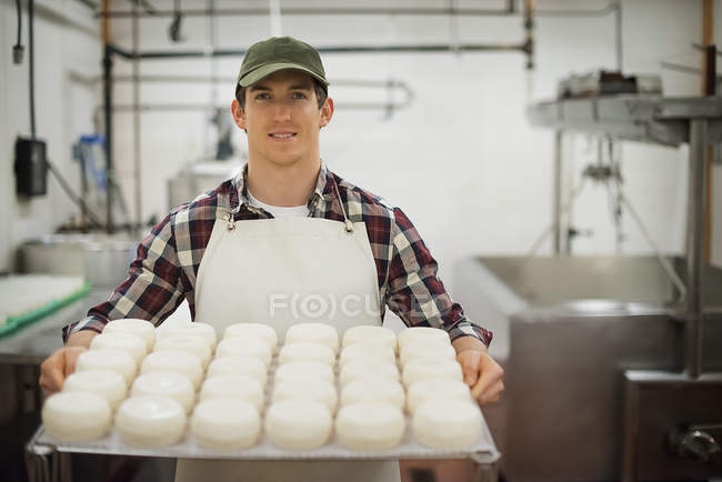 Man with large wheels of cheese maturing. — Stock Photo