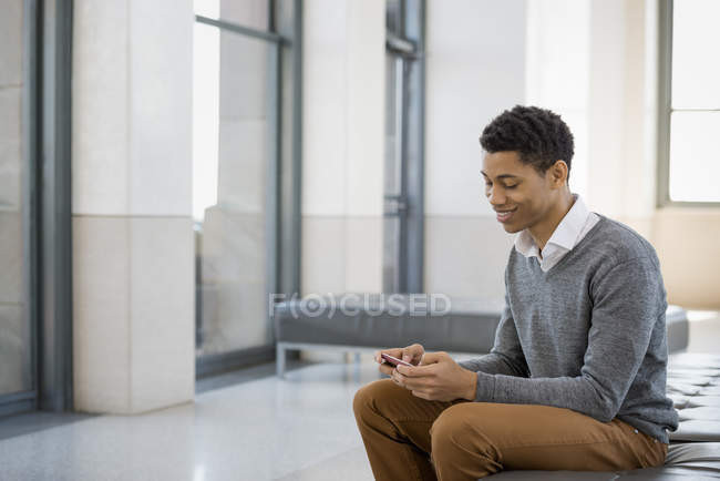 Mann sitzt in einer Lobby auf einer Bank. — Stockfoto