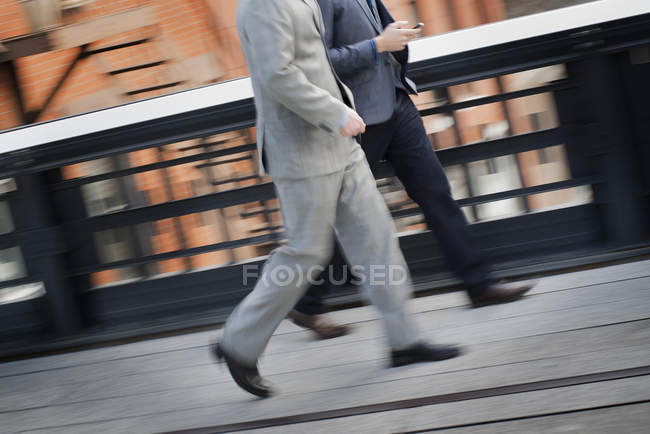 Hombres de negocios caminando por la acera de la ciudad - foto de stock