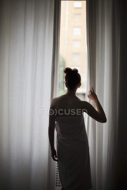 Frau schaut durch Fenster — Stockfoto