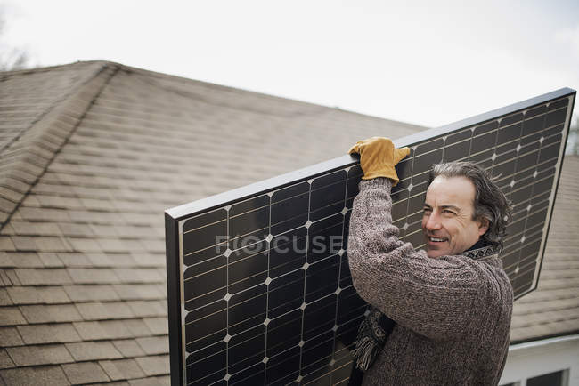 Людина несе велику сонячну панель — стокове фото