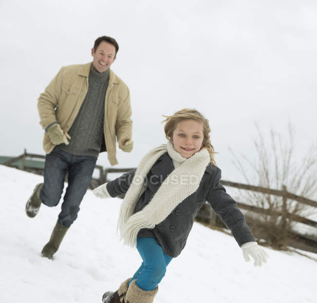 Мужчина гоняется за молодой девушкой по снегу — стоковое фото