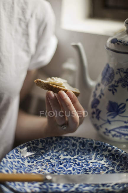 Woman holding a piece of buttered bread. — Stock Photo
