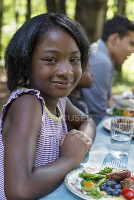 Mädchen und Erwachsene sitzen am Tisch. — Stockfoto