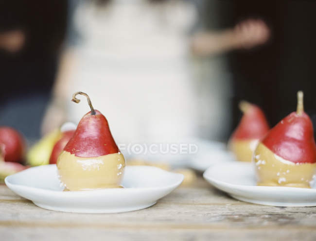 Dipping fresh organic pears into a sauce — Stock Photo