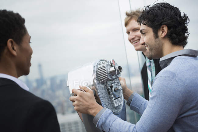 Männer blicken durch ein Teleskop über die Stadt. — Stockfoto