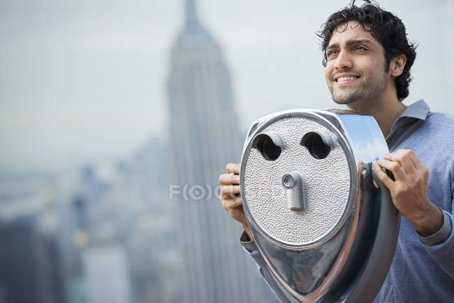 Mann blickt durch ein Teleskop über die Stadt. — Stockfoto