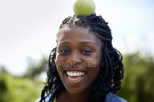 Mujer con manzana verde encima de la cabeza . - foto de stock