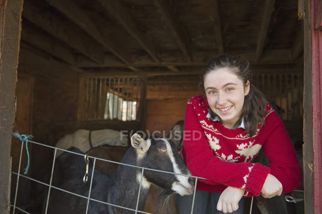 Menina apoiando-se na barreira do galpão de cabra — Fotografia de Stock