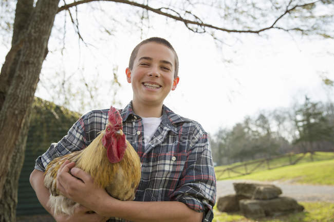 Menino segurando uma galinha — Fotografia de Stock