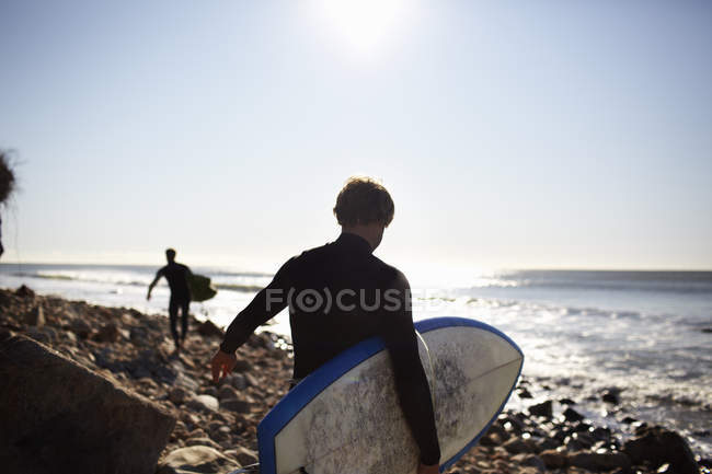 Personas que llevan sus tablas de surf . - foto de stock