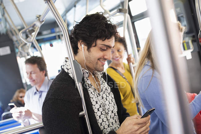 Человек проверяет телефон в городском автобусе — стоковое фото