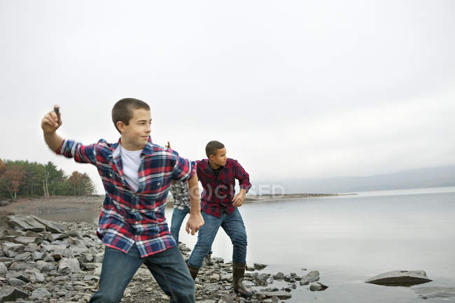 Jungen werfen Kieselsteine über das Wasser. — Stockfoto