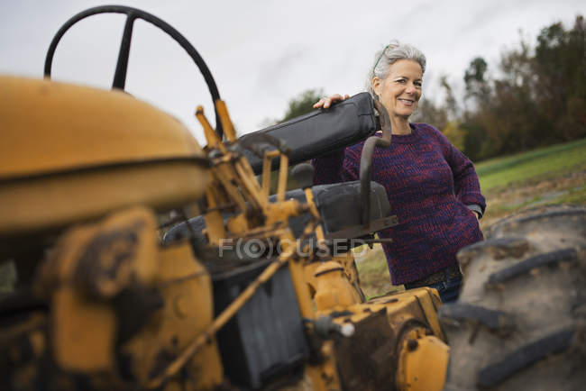 Farmer woman by a tractor. — Stock Photo