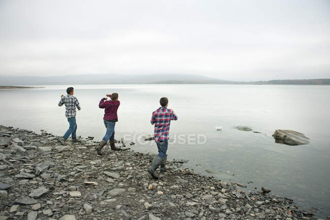 Jungen werfen Kieselsteine über das Wasser. — Stockfoto