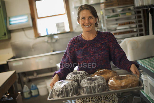 Mulher em uma cozinha com bolos assados frescos . — Fotografia de Stock