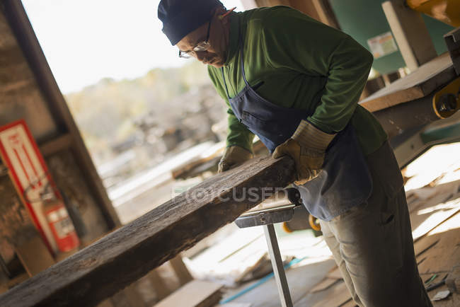 Uomo esaminando una grande tavola di legno tagliato — Foto stock