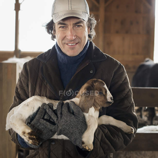 Человек, держащий маленькую козу — стоковое фото