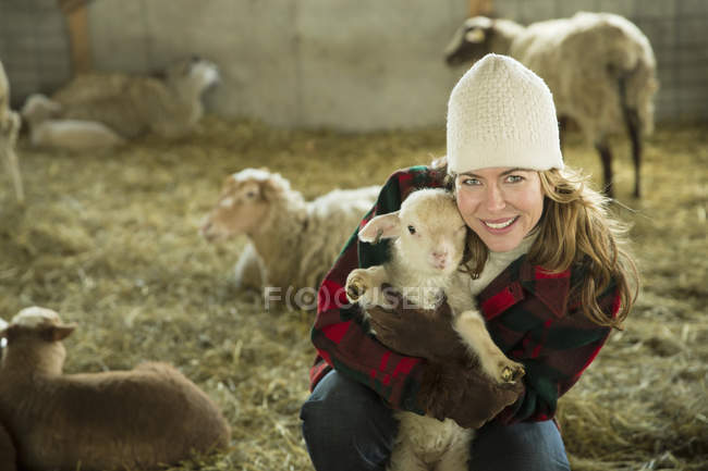 Woman holding a small lamb. — Stock Photo