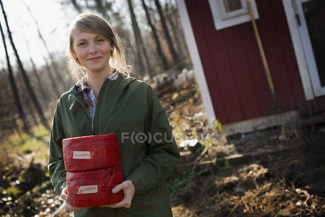 Young woman holding blocks of cheese. — Stock Photo