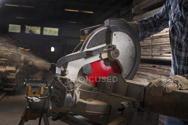 Uomo che utilizza una sega circolare per tagliare il legno . — Foto stock