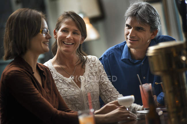 Women and a man sitting at a bar. — Stock Photo