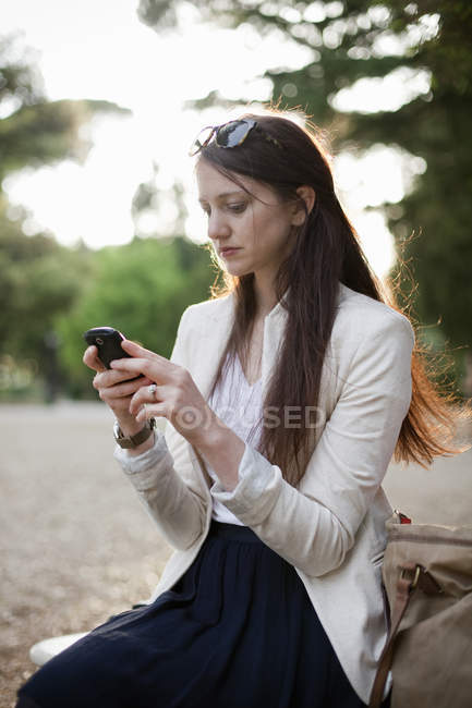 Mujer con teléfono celular en el parque - foto de stock