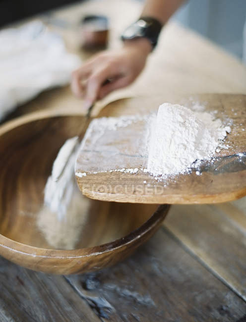 Main verser la farine dans un bol — Photo de stock
