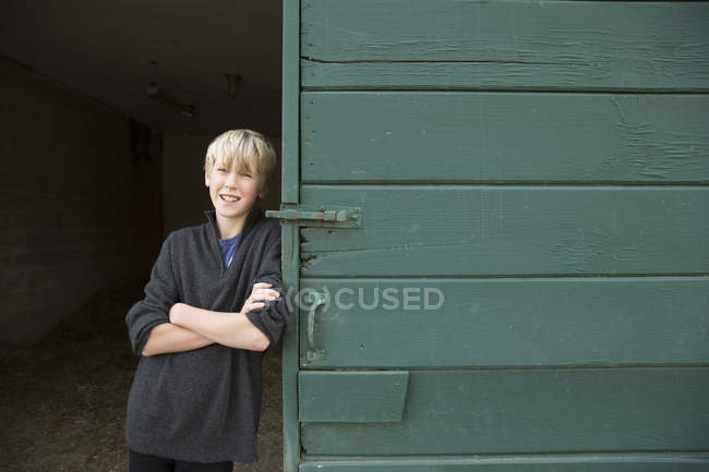 Boy leaning against a barn door — Stock Photo