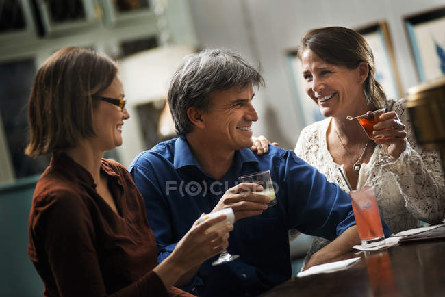 Frauen und ein Mann sitzen an einer Bar. — Stockfoto