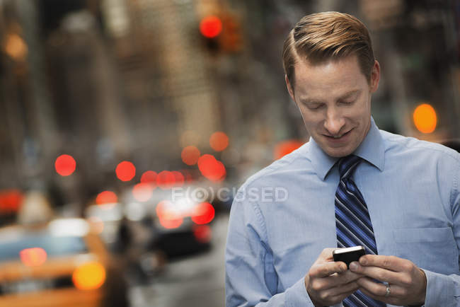 Людина з мобільним телефоном на жвавій вулиці — стокове фото