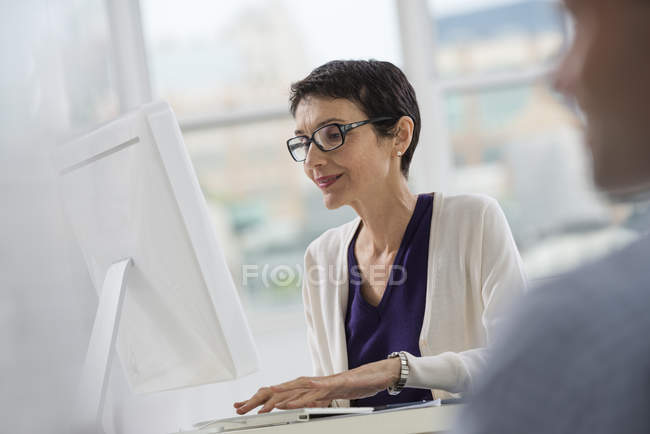 Жінка сидить за столом з комп'ютером — стокове фото