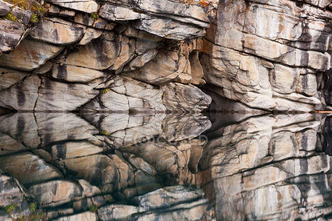 Falaises rocheuses reflétées dans l'eau calme — Photo de stock