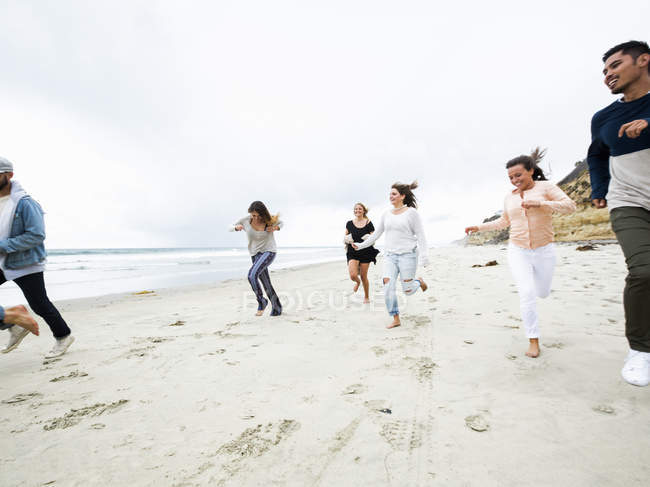 Hombres y mujeres corriendo en una playa - foto de stock