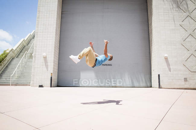 Man somersaulting in front of a garage door. — Stock Photo