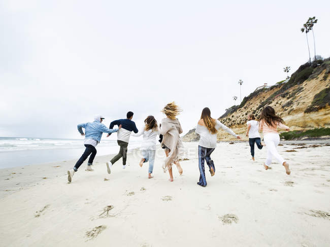 Homens e mulheres correndo em uma praia — Fotografia de Stock