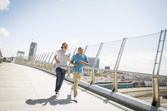 Männer joggen an einer Brücke entlang. — Stockfoto
