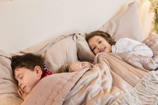 Tre bambini sdraiati in un letto — Foto stock