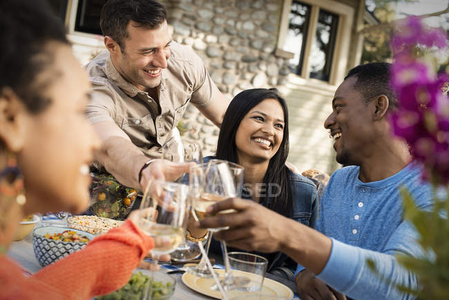 People laughing and clinking wine glasses — Stock Photo