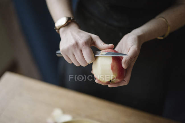 Frau schält mit Messer einen Apfel. — Stockfoto