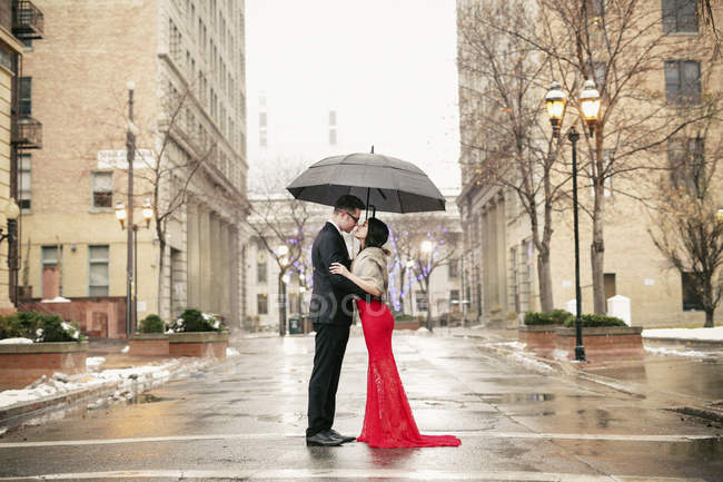Coppia baciarsi sotto un ombrello in città . — Foto stock